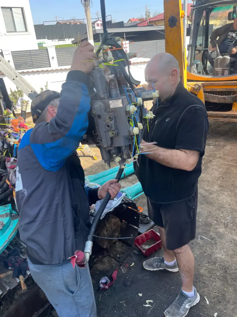 Tehnicieni la blocul de valve al excavatorului Kobelco.