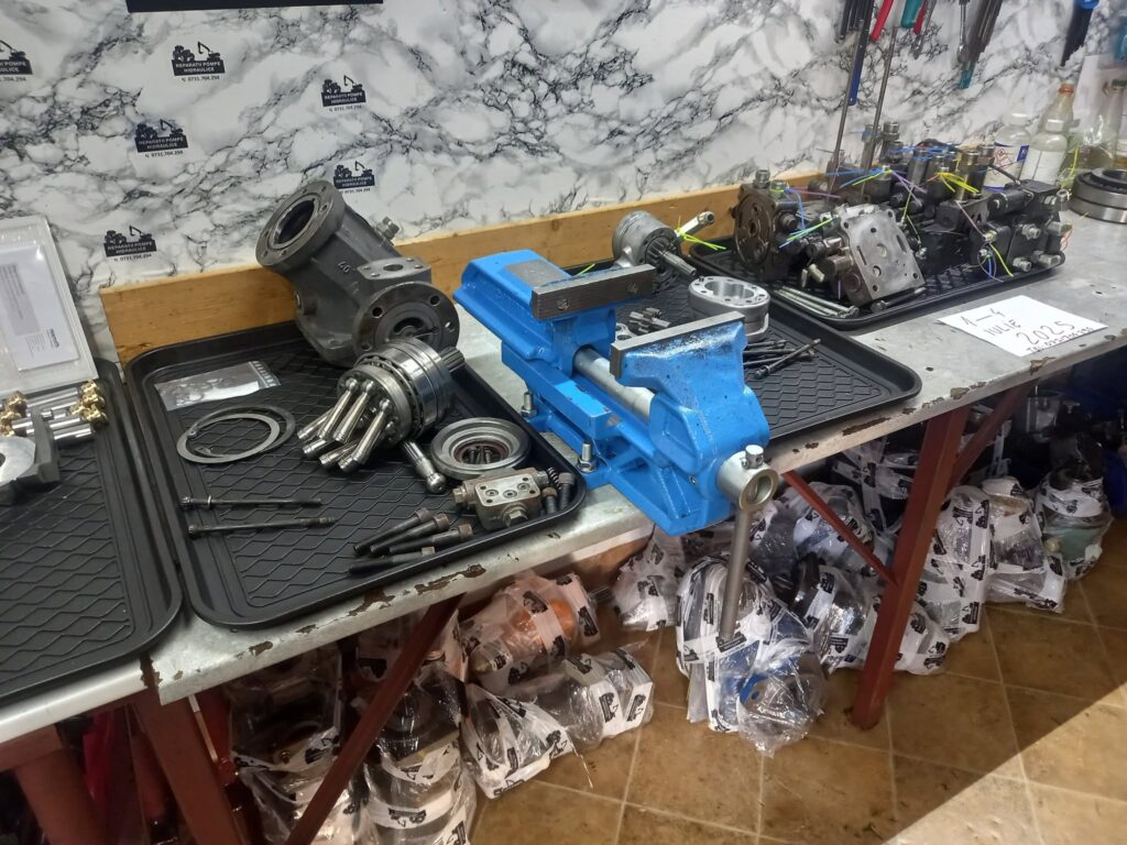 Bancul de lucru din atelier, cu pompă hidraulică desfăcută, menghină și scule
