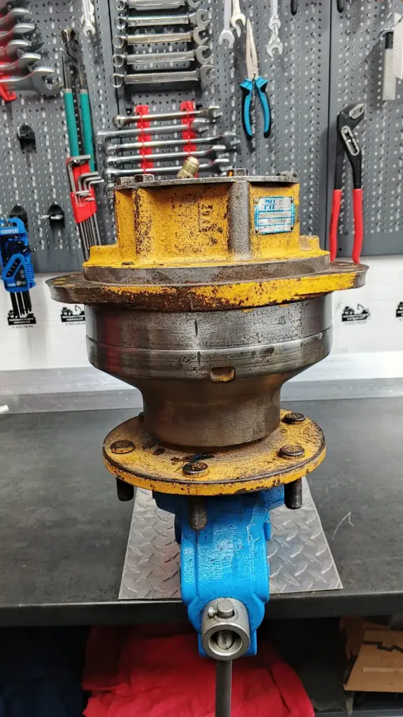 Hidromotor Poclain Hydraulics fixat în menghină pe bancul de lucru, cu plăcuța de identificare pe corp